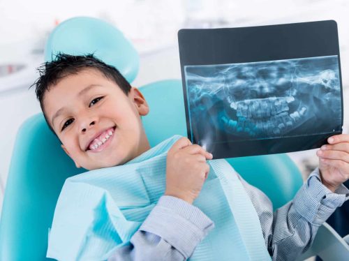 Happy boy at the dentist holding an x-ray